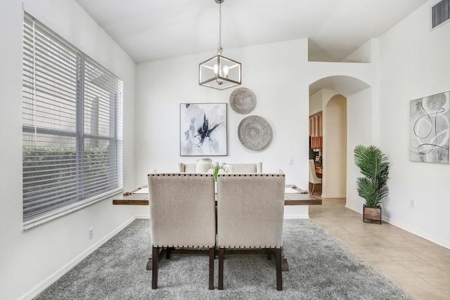 dining area featuring tile patterned flooring, a healthy amount of sunlight, and an inviting chandelier