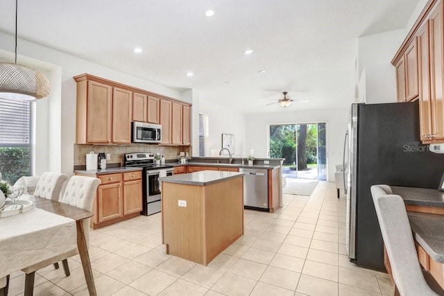 kitchen with a center island, ceiling fan, decorative light fixtures, kitchen peninsula, and stainless steel appliances