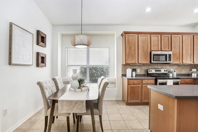 kitchen featuring light tile patterned floors, stainless steel appliances, hanging light fixtures, and tasteful backsplash