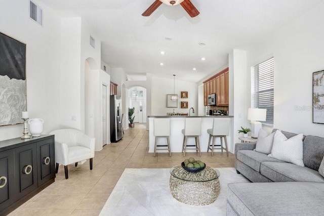 living room with light tile patterned floors, vaulted ceiling, ceiling fan, and sink