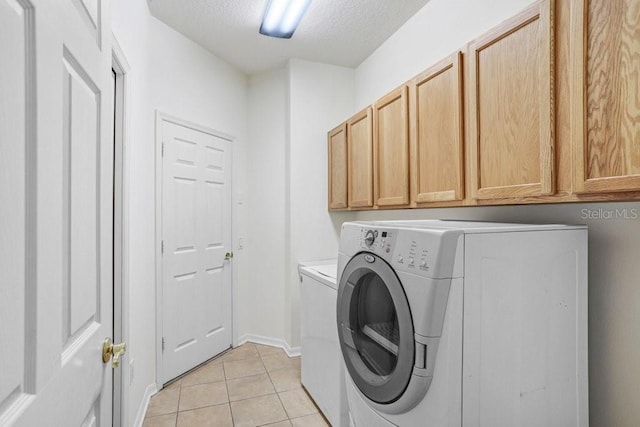 clothes washing area featuring washer and clothes dryer, light tile patterned floors, cabinets, and a textured ceiling