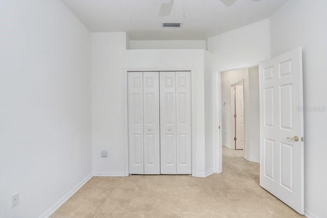 unfurnished bedroom with ceiling fan, light tile patterned flooring, and a closet