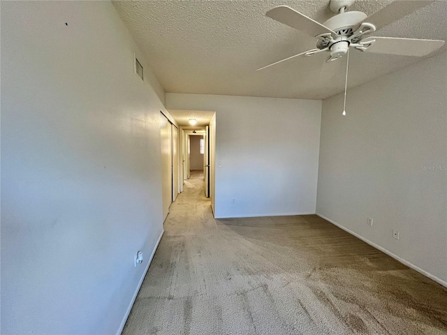 carpeted spare room featuring ceiling fan and a textured ceiling