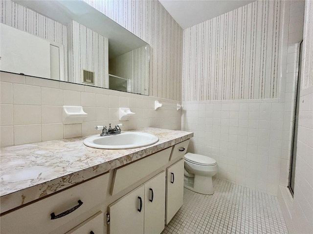 bathroom with tile patterned floors, vanity, tile walls, and walk in shower