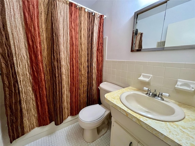 full bathroom with tile patterned floors, toilet, shower / bath combo with shower curtain, vanity, and tile walls