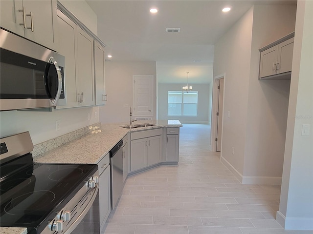 kitchen with an inviting chandelier, sink, gray cabinets, light stone countertops, and stainless steel appliances