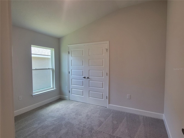 unfurnished bedroom with carpet floors, a closet, vaulted ceiling, and multiple windows