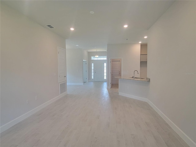 unfurnished living room with light hardwood / wood-style floors and sink