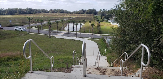 view of community featuring a rural view, a water view, and a lawn