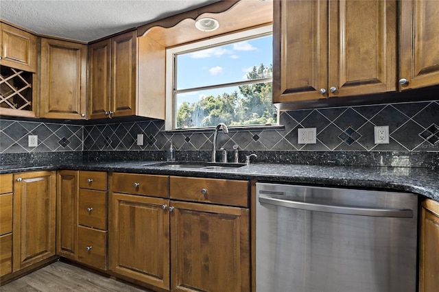 kitchen featuring dark stone counters, dishwasher, sink, and light hardwood / wood-style floors