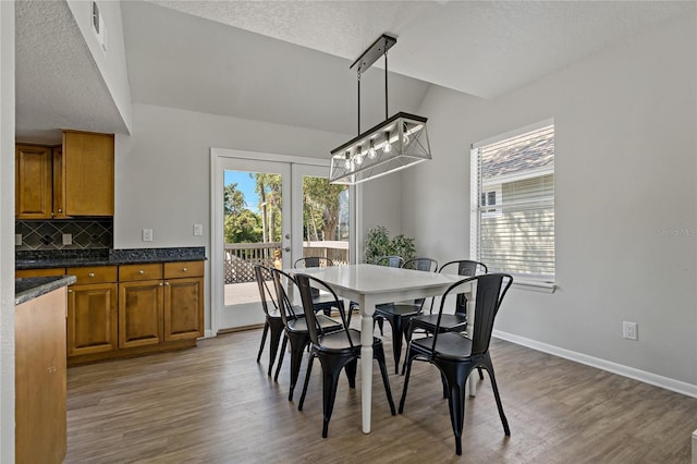 dining room featuring wood-type flooring, a textured ceiling, a wealth of natural light, and french doors