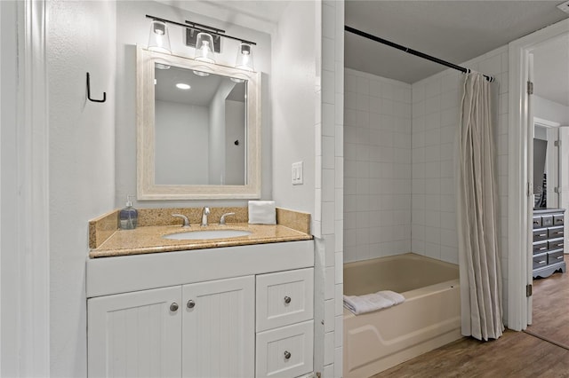 bathroom with hardwood / wood-style floors, vanity, and shower / bath combo