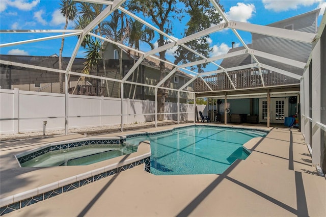 view of swimming pool featuring a patio area, glass enclosure, and an in ground hot tub