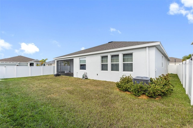 rear view of property featuring central AC unit, a sunroom, and a yard