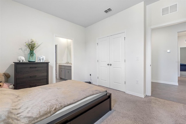 bedroom featuring ensuite bathroom, light colored carpet, sink, and a closet