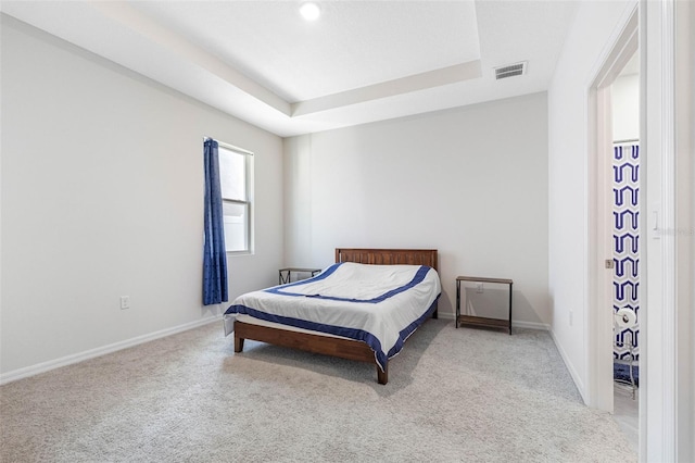 bedroom with a tray ceiling and light colored carpet