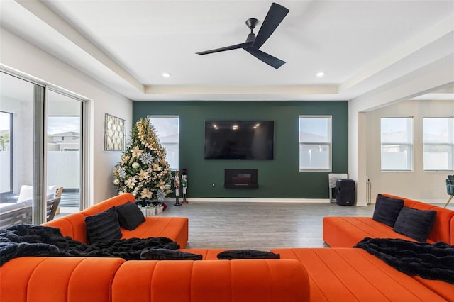 living room with hardwood / wood-style floors, ceiling fan, and a tray ceiling