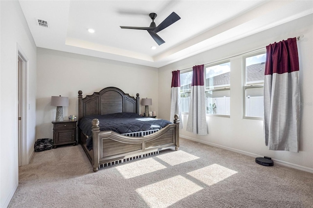 bedroom featuring a raised ceiling, ceiling fan, and light carpet