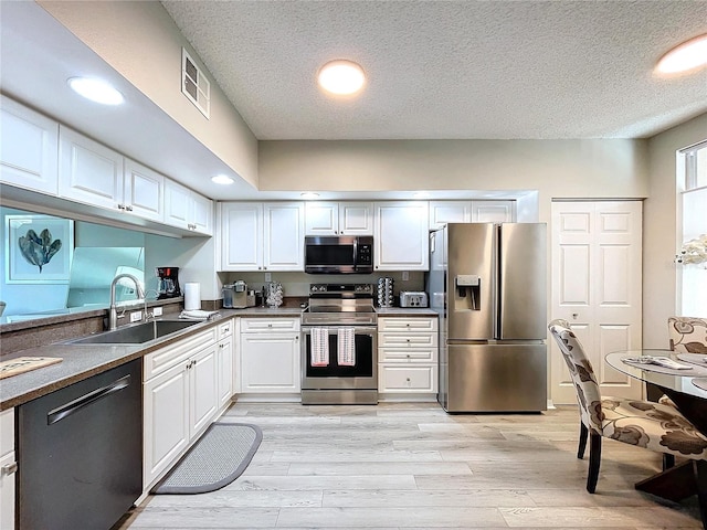 kitchen with stainless steel appliances, white cabinetry, light hardwood / wood-style floors, and sink