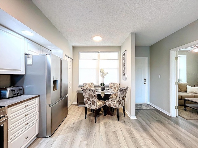 dining area with a textured ceiling and light hardwood / wood-style flooring