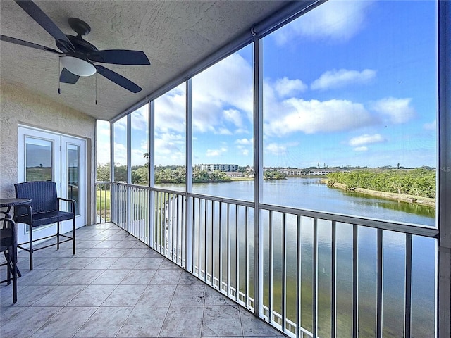 sunroom featuring ceiling fan, a water view, and a wealth of natural light