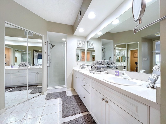 bathroom with tile patterned floors, vanity, and a shower with door