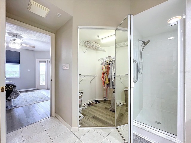 bathroom featuring tile patterned flooring, a tile shower, a textured ceiling, and ceiling fan