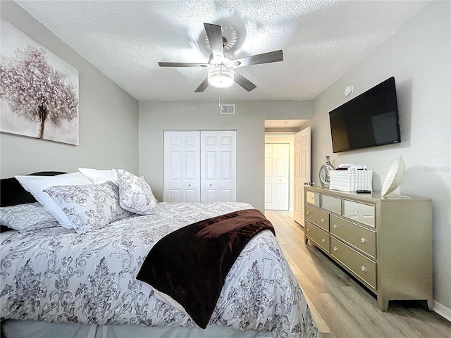 bedroom featuring light wood-type flooring, a textured ceiling, a closet, and ceiling fan