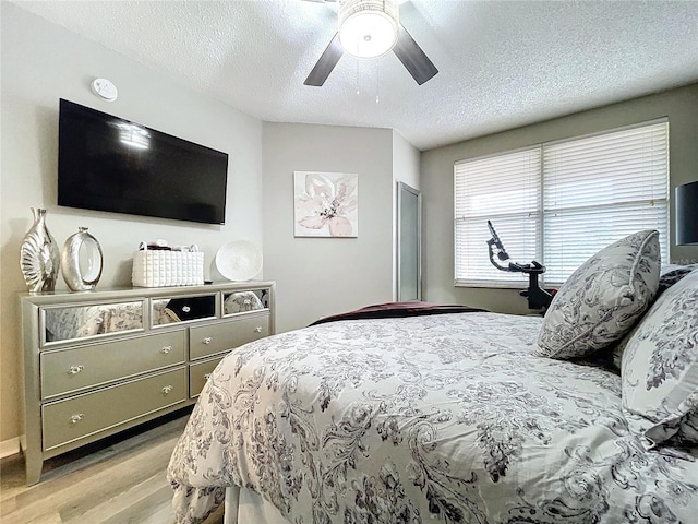 bedroom featuring ceiling fan, a textured ceiling, and light hardwood / wood-style flooring