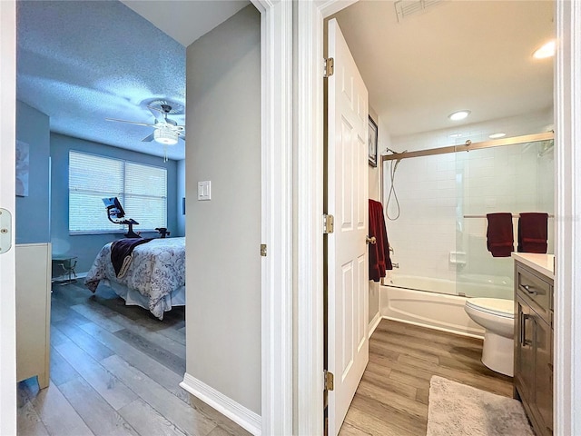 full bathroom with hardwood / wood-style floors, ceiling fan, enclosed tub / shower combo, and a textured ceiling