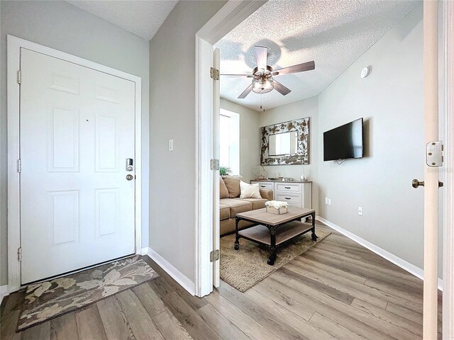 living room featuring ceiling fan, light hardwood / wood-style floors, and a textured ceiling