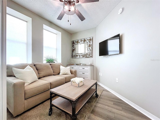 living room with ceiling fan, a textured ceiling, and light hardwood / wood-style flooring