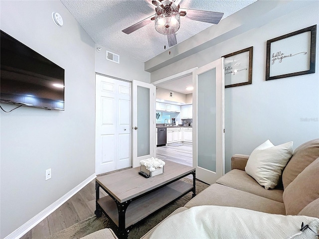 living room featuring hardwood / wood-style flooring, ceiling fan, and a textured ceiling