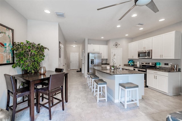 kitchen featuring a center island, a breakfast bar, white cabinets, and stainless steel appliances