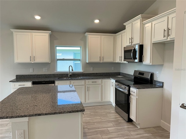 kitchen with white cabinetry, sink, a center island, dark stone countertops, and appliances with stainless steel finishes