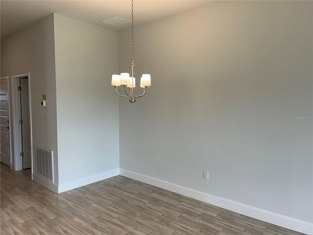 unfurnished room featuring light hardwood / wood-style flooring and an inviting chandelier