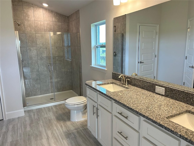 bathroom with hardwood / wood-style floors, vanity, toilet, and a shower with door