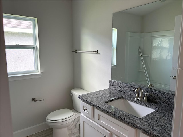 bathroom featuring a wealth of natural light, vanity, toilet, and walk in shower