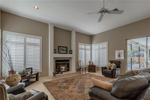 living room featuring a tile fireplace, light tile patterned floors, a wealth of natural light, and ceiling fan