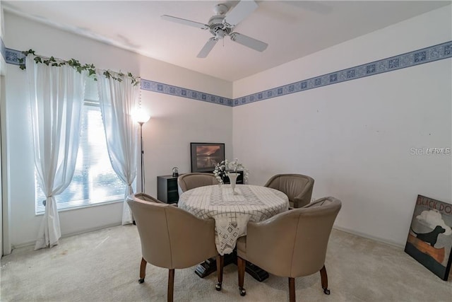 dining area with ceiling fan and light carpet