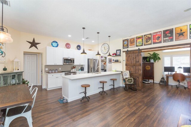10328 Henderson St, Spring Hill, FL 34608 - kitchen featuring a barn door, pendant lighting, a breakfast bar, white cabinets, and appliances with stainless steel finishes
