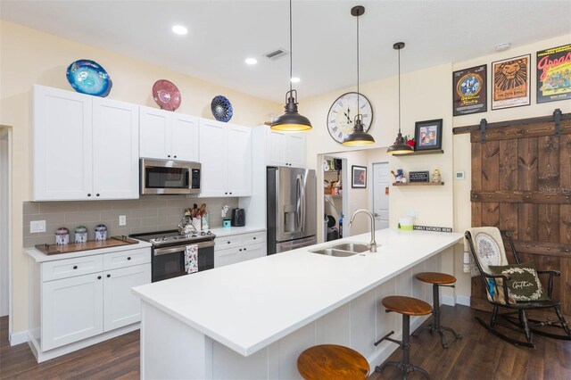 10328 Henderson St, Spring Hill, FL 34608 - kitchen featuring white cabinetry, sink, a barn door, pendant lighting, and appliances with stainless steel finishes