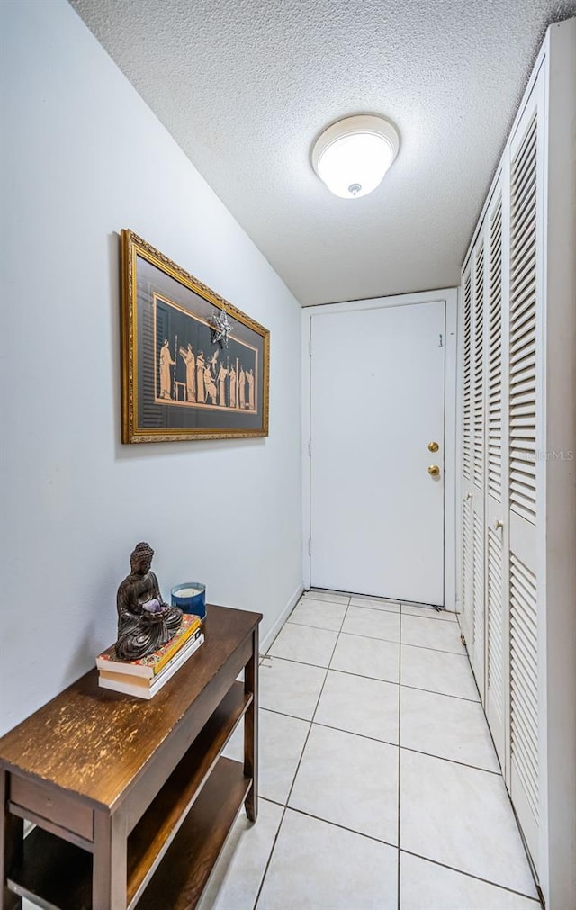 doorway to outside featuring a textured ceiling and light tile patterned flooring