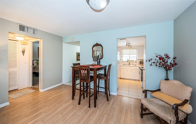 dining area featuring a textured ceiling, light wood-type flooring, and sink