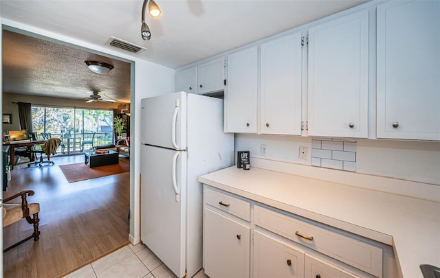 kitchen with white refrigerator, ceiling fan, light tile patterned floors, a textured ceiling, and white cabinetry