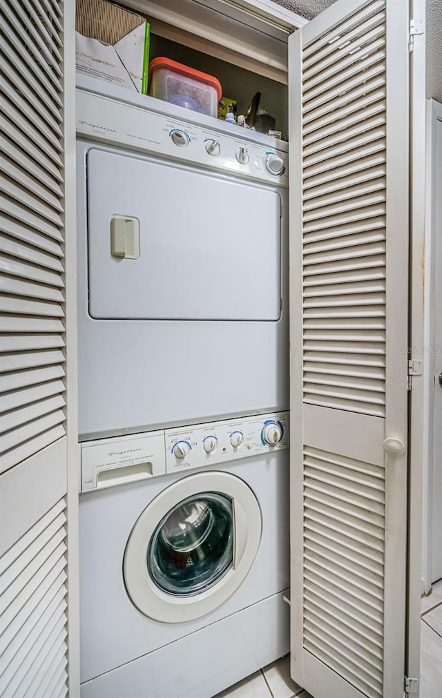 clothes washing area featuring stacked washer / drying machine and light tile patterned floors