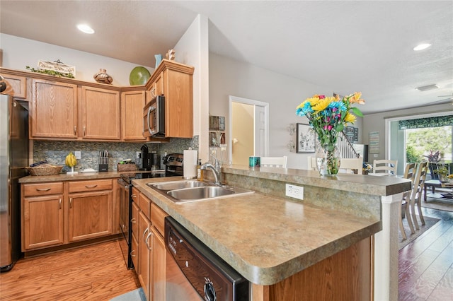 kitchen featuring sink, decorative backsplash, appliances with stainless steel finishes, light hardwood / wood-style floors, and kitchen peninsula