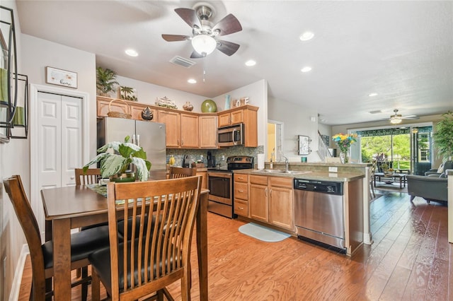 kitchen with ceiling fan, sink, stainless steel appliances, light hardwood / wood-style flooring, and backsplash