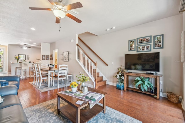 living room featuring hardwood / wood-style flooring, ceiling fan, and a textured ceiling