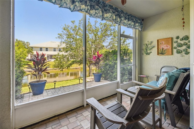 sunroom featuring a water view, ceiling fan, and a healthy amount of sunlight